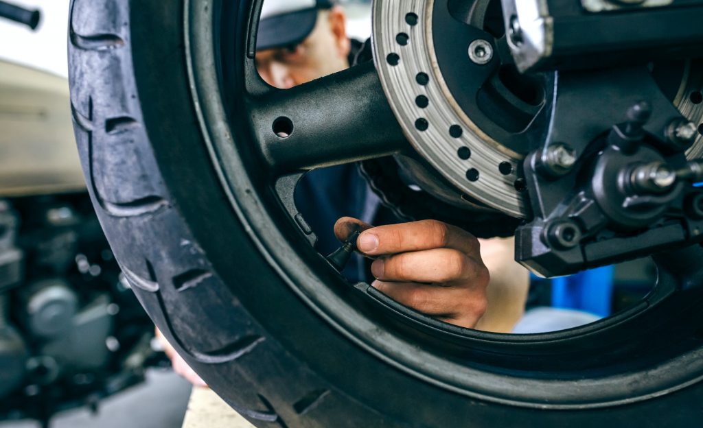 Mechanic placing motorcycle wheel valve